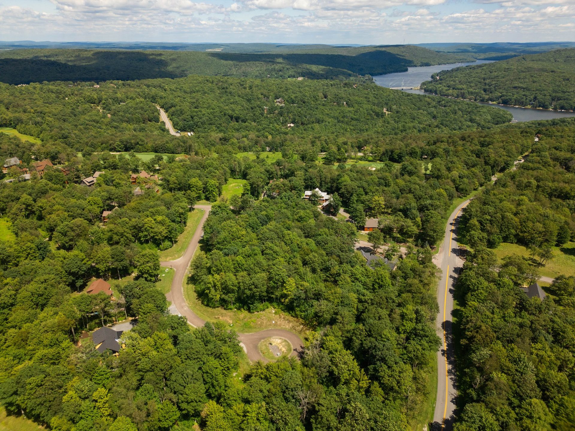 Aerial view over the ridge: the Eagle's Perch sits in the trees at lower left, the Lodestone golf course runs through the middle, and Deep Creek Lake is on the horizon at upper right