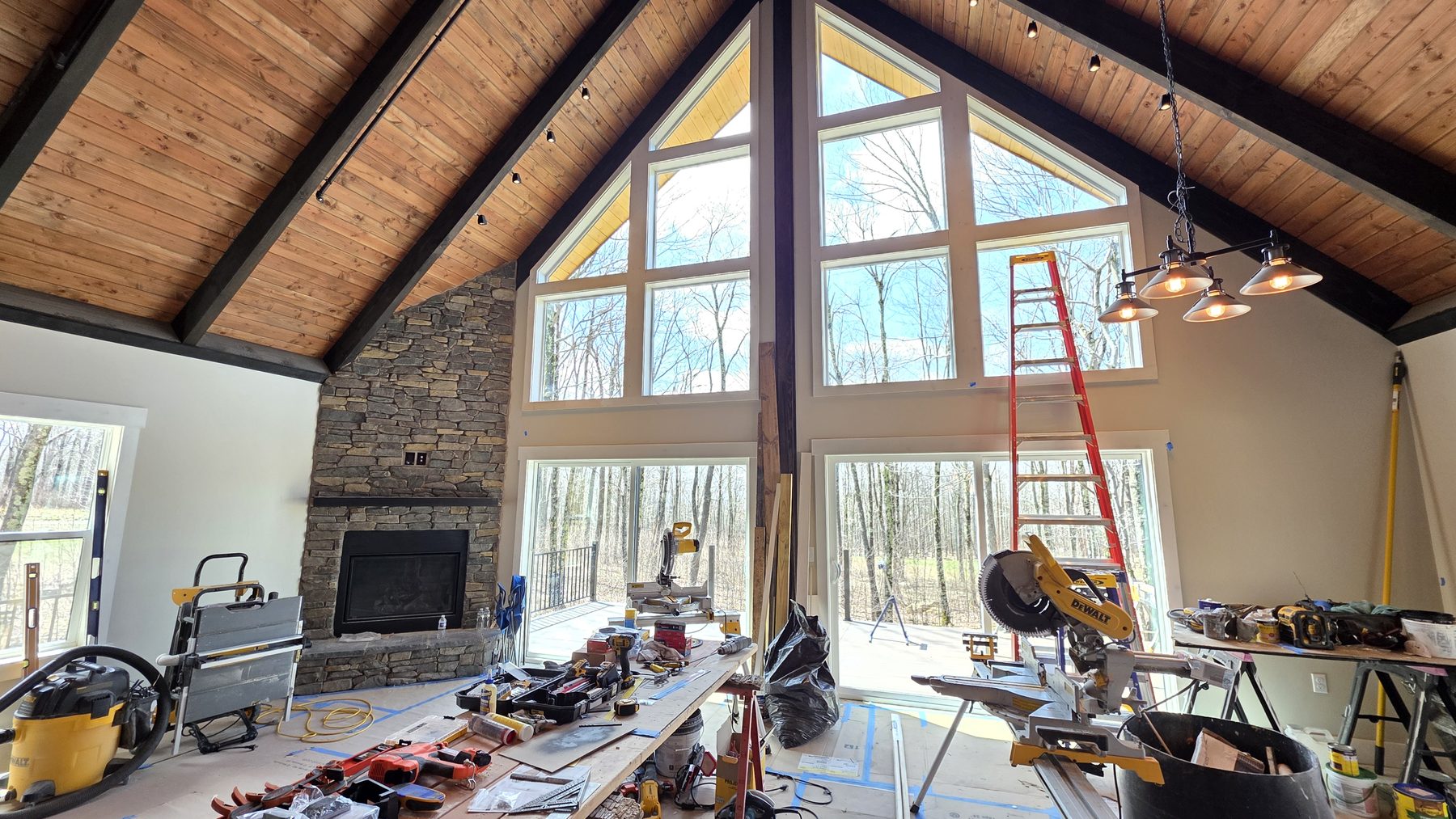 Great room with vaulted wood ceilings, stone fireplace, and floor-to-ceiling windows