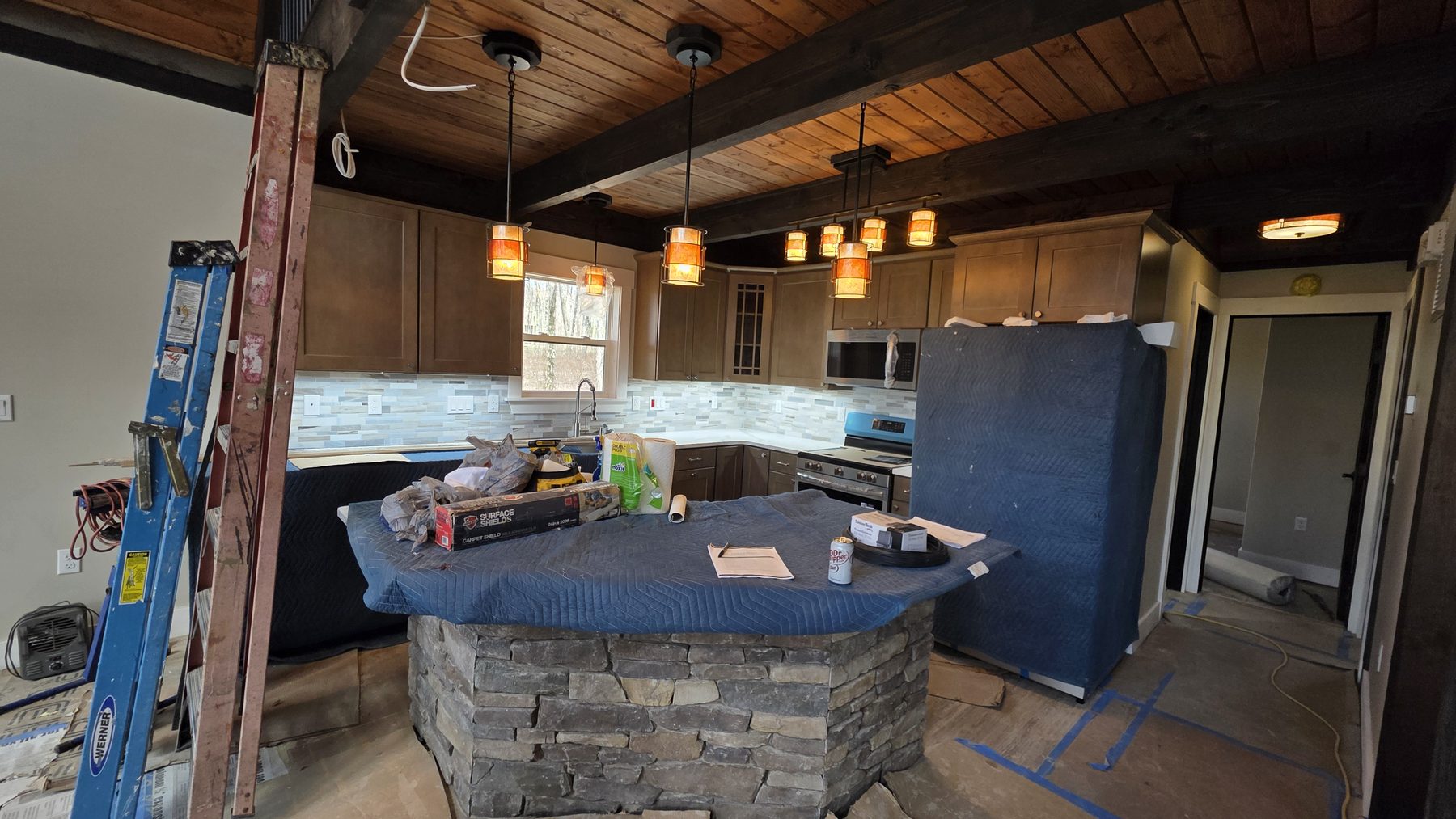Kitchen with custom lighting, wood ceiling beams, and stone island