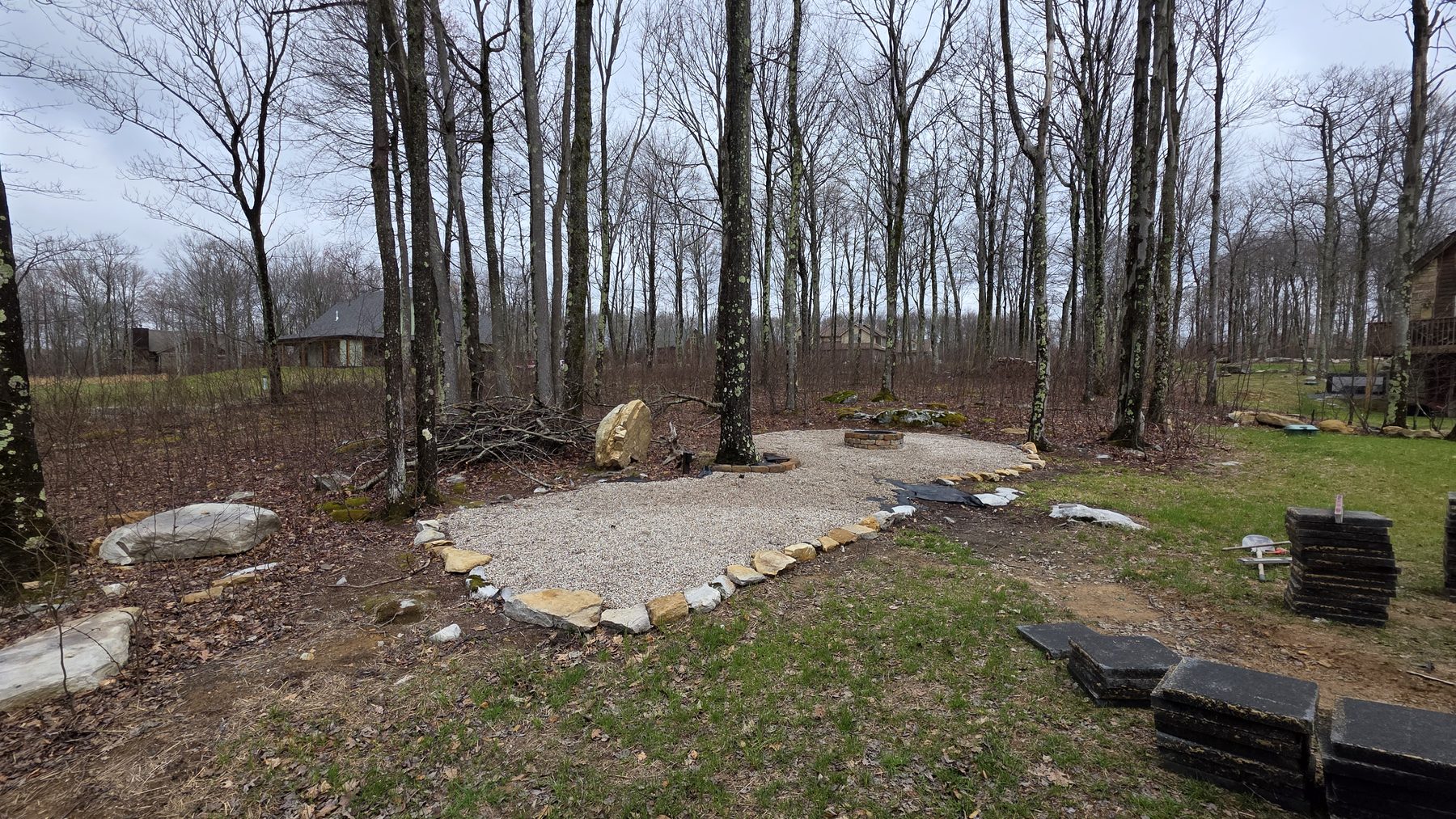 Outdoor gravel patio with fire pit area in the wooded backyard