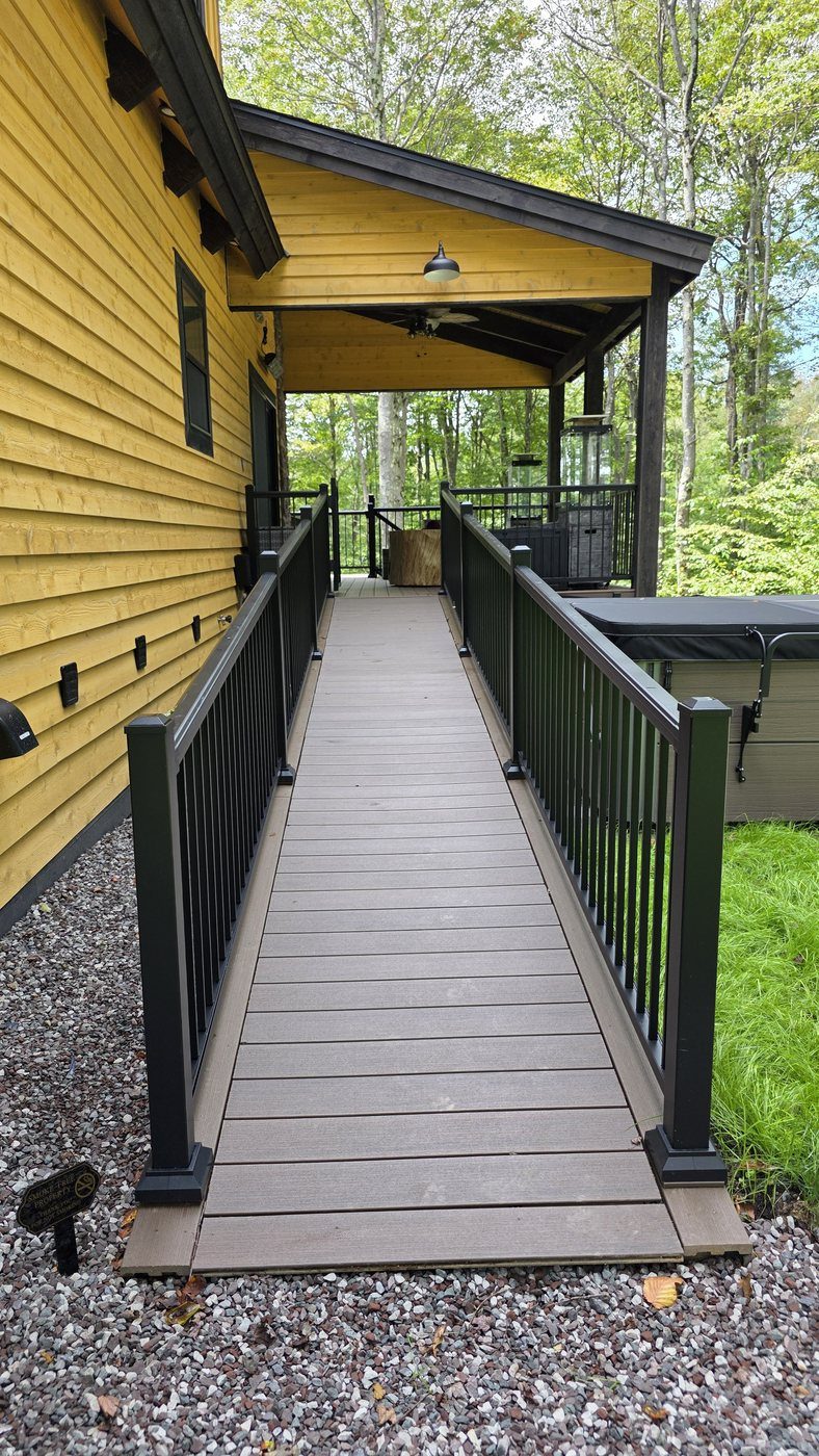 The wheelchair ramp at the back of the house running up to the covered deck, with railings on both sides