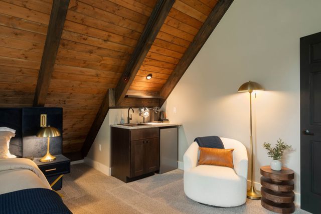 The primary suite from the landing — the gable, the king, and the treetops